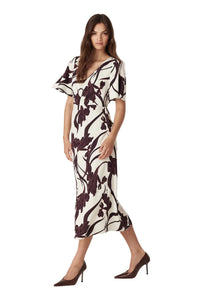 Woman wearing a black and white floral dress on a plain background