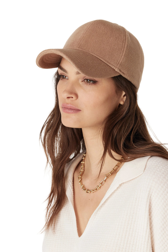 Woman wearing a brown cap and gold necklace on a white background