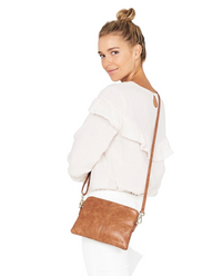 Woman wearing a white outfit with a brown crossbody bag on a white background