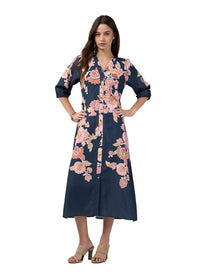 A woman modeling a navy blue midi wrap dress with a pink and peach floral print, styled with beige heeled sandals against a light gray studio background.