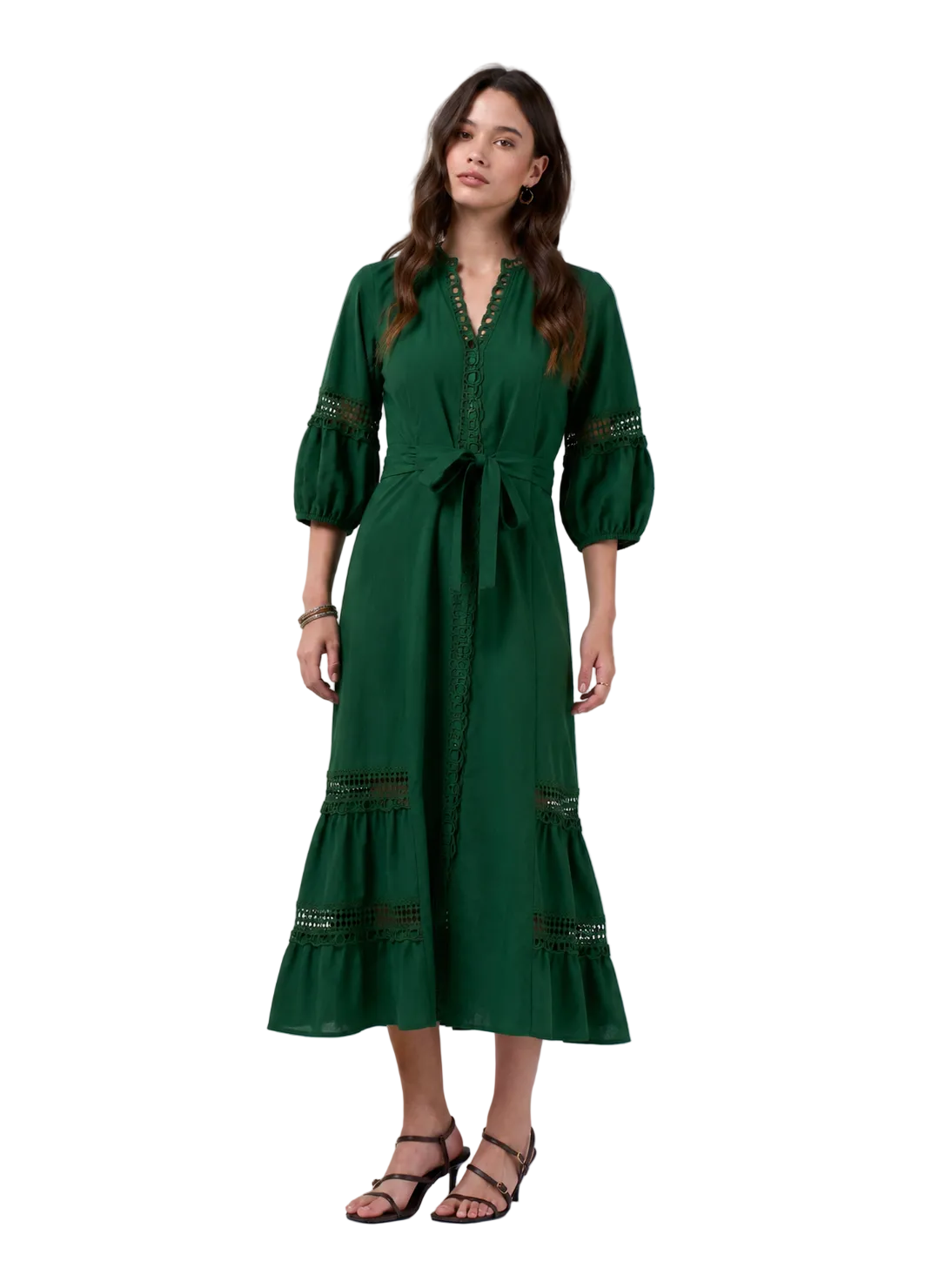 A woman modeling a dark green midi dress with three-quarter puff sleeves, a matching waist tie, and decorative embroidered details on the cuffs and hem, paired with black strappy heels against a light gray studio background.