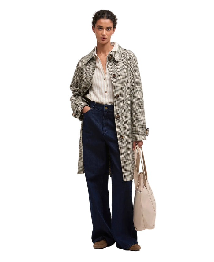 Woman wearing a plaid coat and holding a beige bag on a white background