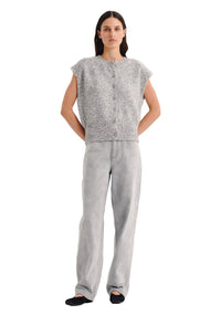 Woman wearing a gray sleeveless knitted top and pants on a white background