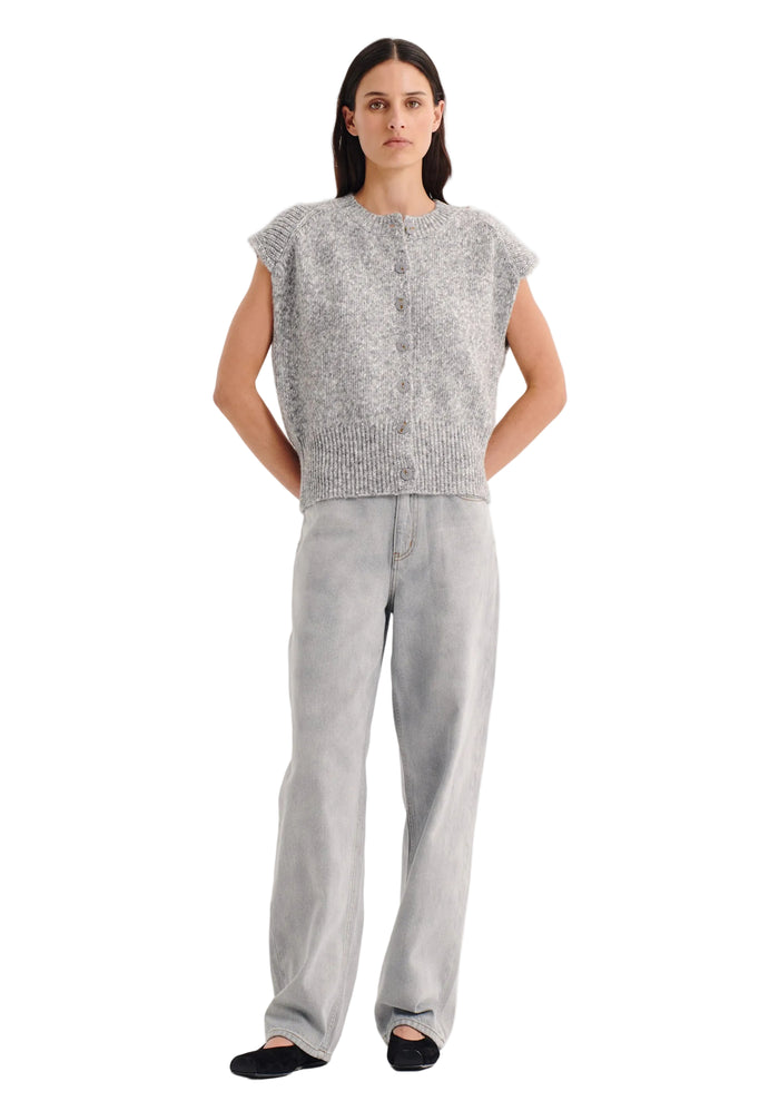 Woman wearing a gray sleeveless knitted top and pants on a white background