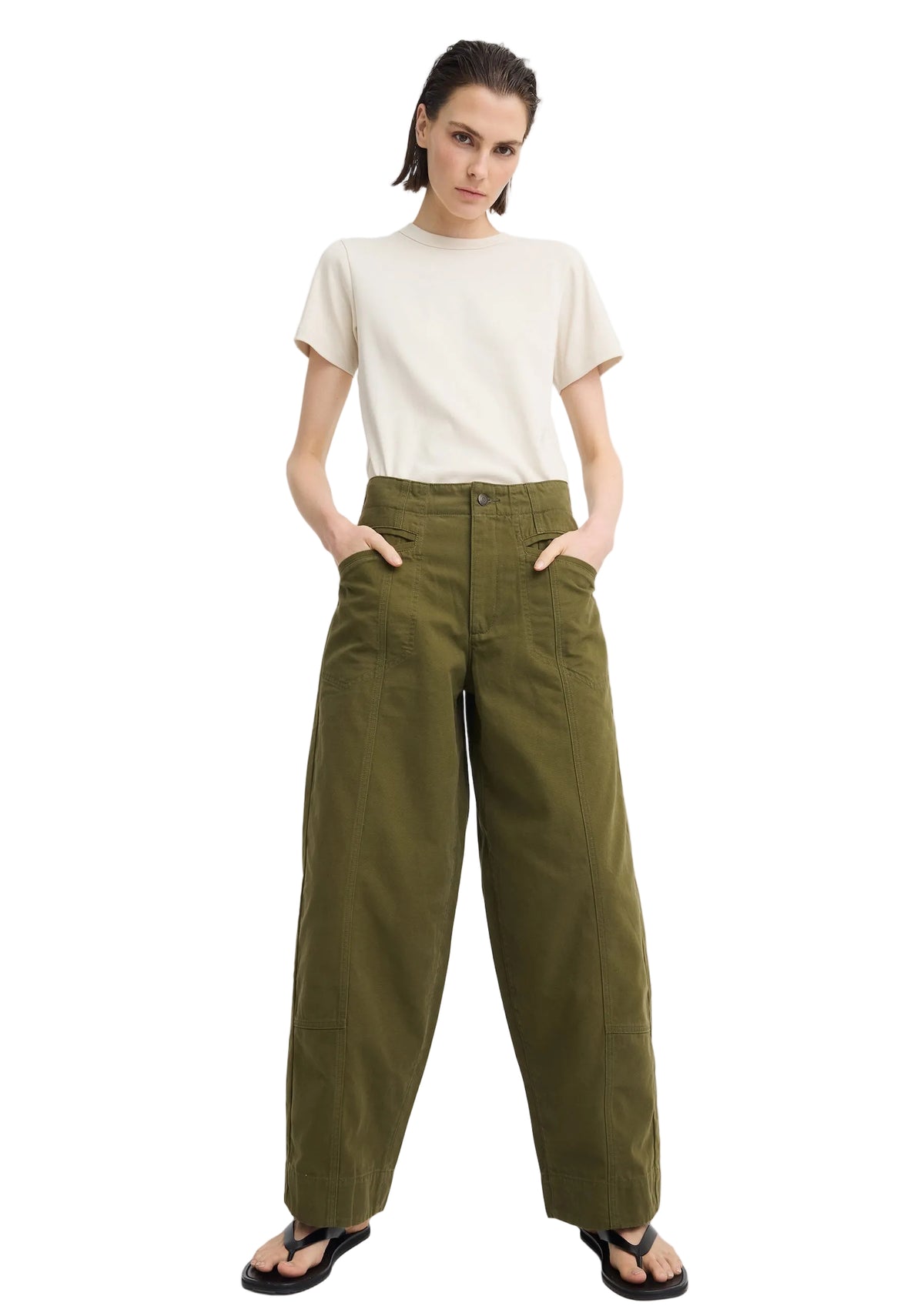 A model wearing olive green wide-leg trousers, a cream short-sleeve t-shirt, and black sandals, standing against a light gray studio background.
