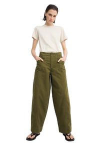 A model wearing olive green wide-leg trousers, a cream short-sleeve t-shirt, and black sandals, standing against a light gray studio background.