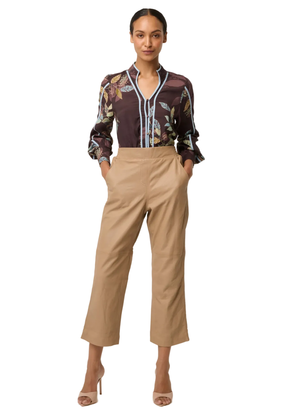 Woman wearing a patterned blouse and beige pants on a white background