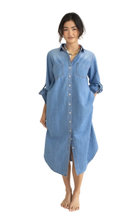A woman modeling a light blue denim shirt dress with a button-down front, three-quarter sleeves, and chest pockets, standing against a plain off-white background.