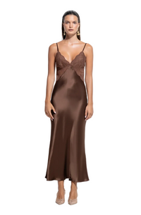 A woman modeling a floor-length satin slip dress in a rich brown color, featuring a lace-trimmed V-neckline and thin spaghetti straps, set against a plain white studio background.